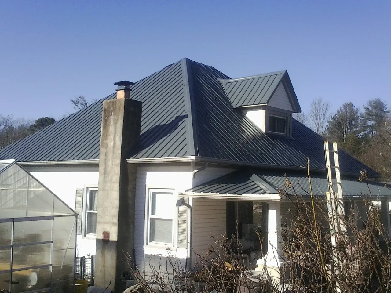 Dark blue standing seam metal roof on a white farmhouse with dormer — Slate & Tile Roof Repair by Roofing Brothers in Denham Springs