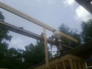 Carpenter setting a ridge beam over a new addition frame — Ice Dam Removal by Roofing Brothers in Denham Springs