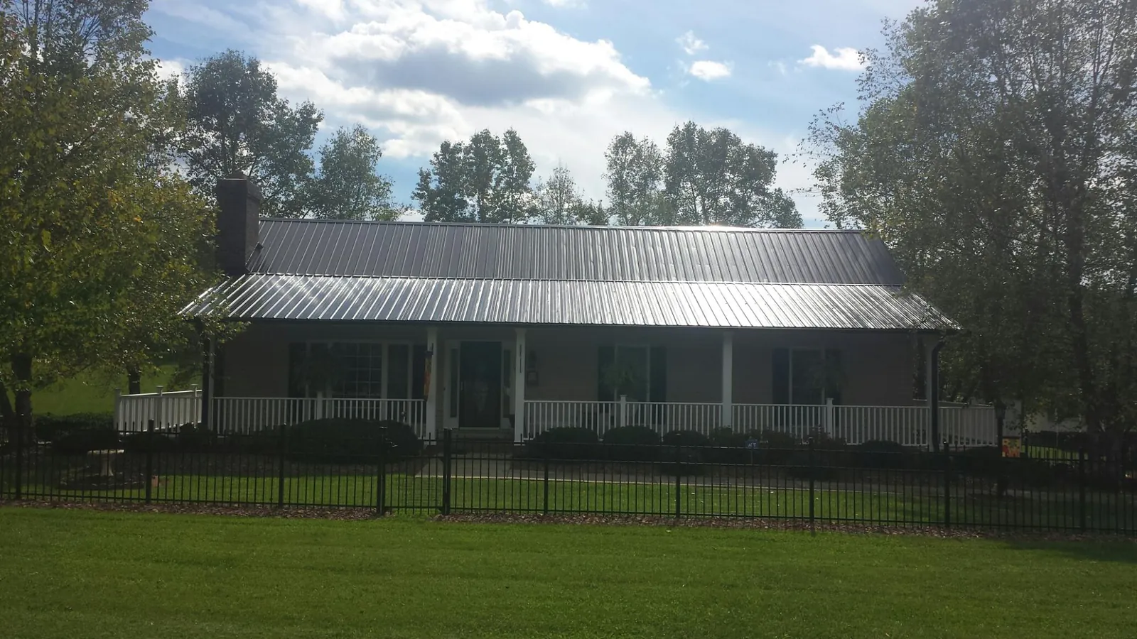 Gray metal roof on a brick ranch with a full width front porch — Gutter Guard Installation work by our crew in Denham Springs
