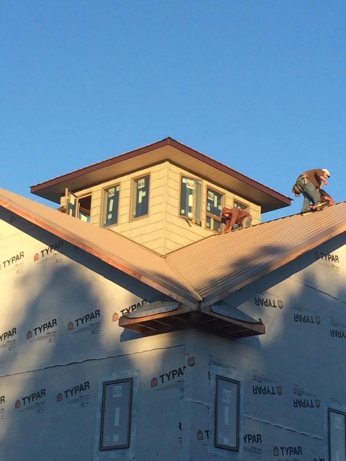 Roofers working around a rooftop cupola on a new metal roof at sunset — Roof Waterproofing in Denham Springs by Roofing Brothers